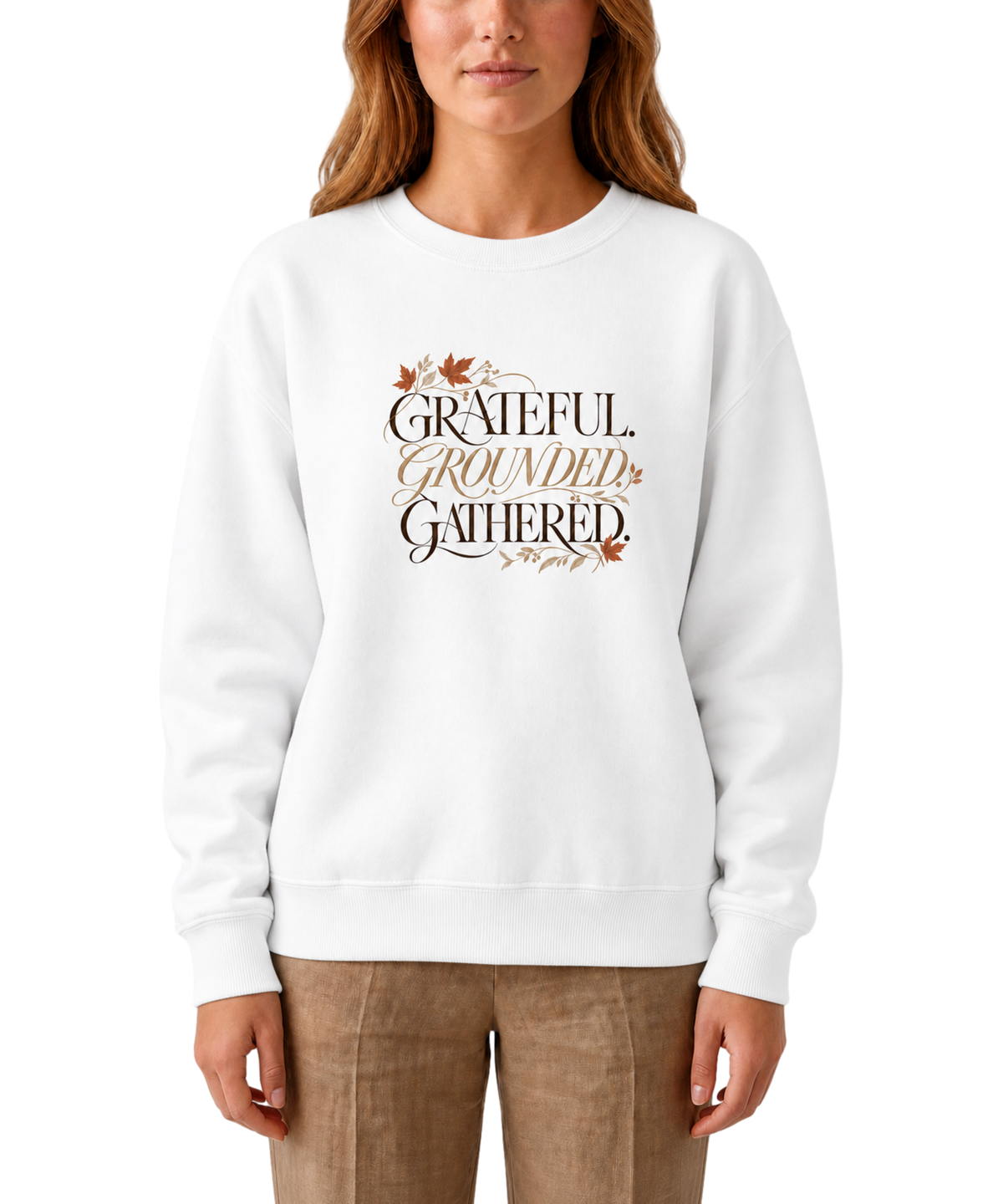 Model wearing a white ‘Grateful. Grounded. Gathered.’ sweatshirt with dark and muted gold lettering and autumn leaf accents.