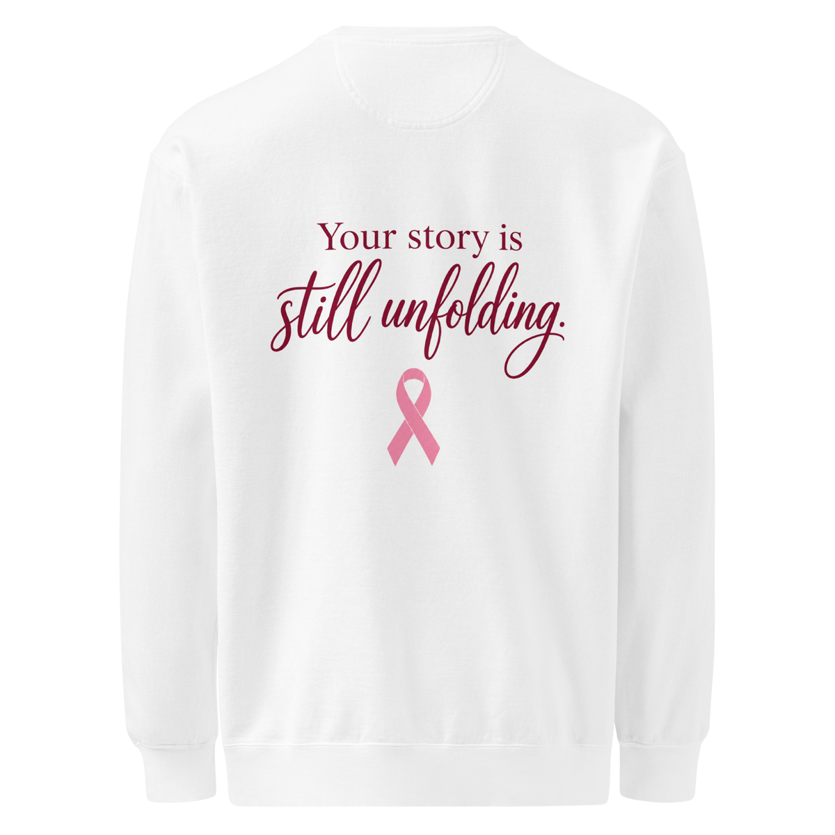 Back of white sweatshirt with burgundy “Your story is still unfolding” lettering above a pink breast cancer awareness ribbon.