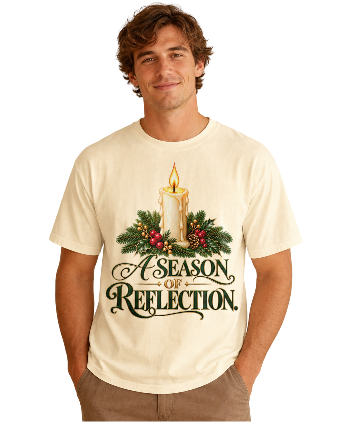 Man wearing an Ivory “A Season of Reflection” Christmas tee featuring a lit candle, evergreen branches, red berries, and green-and-gold lettering, paired with brown pants.