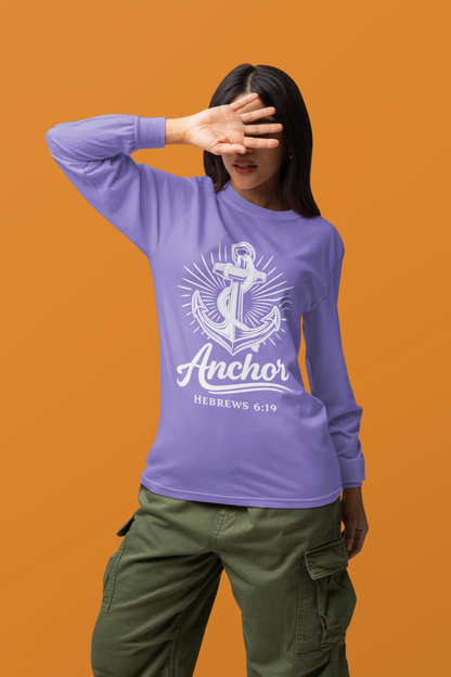 A woman wearing a lavender long-sleeve graphic shirt with a white anchor design and the text 'Anchor' and 'HEBREWS 6:19', paired with olive green cargo pants, set against a solid orange background.