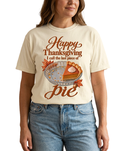 Woman wearing an ivory “I Call the Last Piece of Pie” tee featuring a pumpkin-pie slice and autumn leaves, paired with light blue jeans in a warm neutral interior.