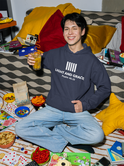Person wearing a hoodie with text, sitting on a bed with snacks and games around