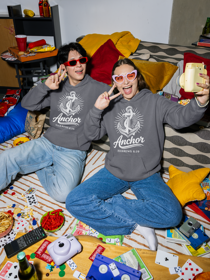 Two people wearing Anchor denim hoodies sitting on a couch with a messy table in front of them.
