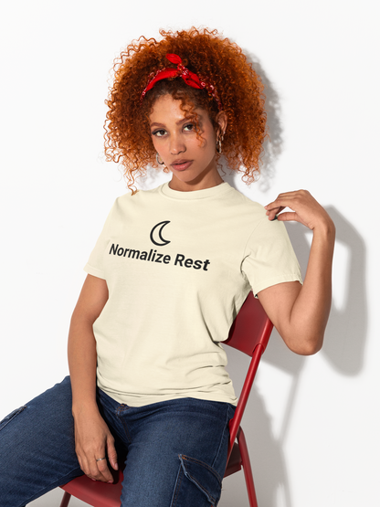 Person wearing a 'Normalize Rest' t-shirt sitting on a red chair against a white background