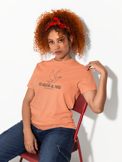 Woman wearing a peach-colored t-shirt with text, sitting on a red chair against a white background