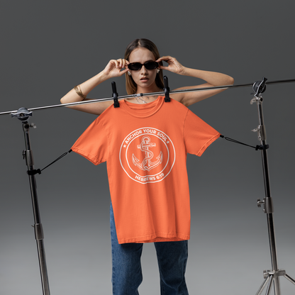 Person wearing an orange t-shirt with a graphic design, standing in front of a gray background