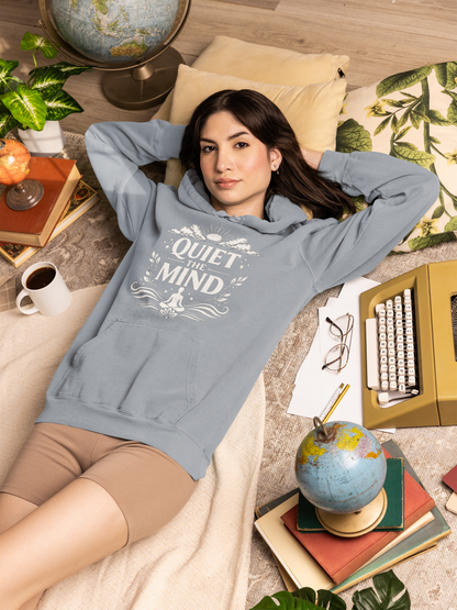 Woman wearing a hoodie with text, lying on a cozy floor with books and globes.