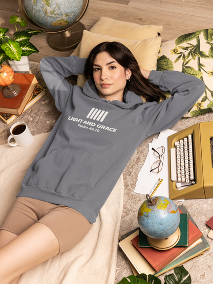 Woman wearing a hoodie with text, lying on a cozy floor with books and globes.
