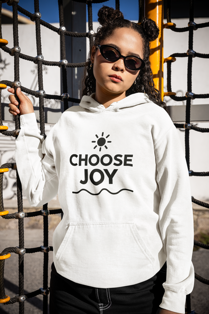 Person wearing a white hoodie with 'CHOOSE JOY' text, standing in front of playground equipment.