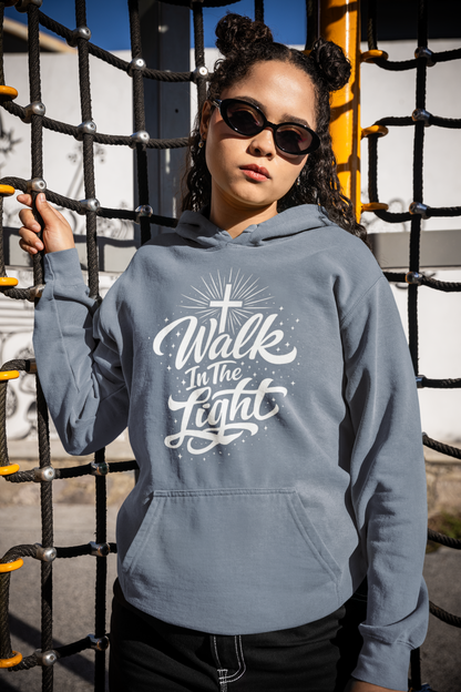 Person wearing a blue jean hoodie with 'Walk In The Light' text, standing in front of playground equipment.