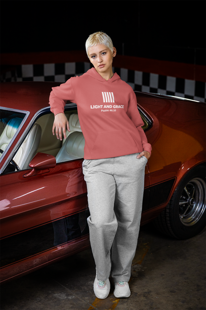 Person wearing a crimson (pinkish) hoodie with text standing next to a red car in a checkered garage.