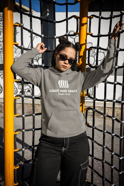 Person wearing a gray hoodie with text, standing in front of playground equipment.