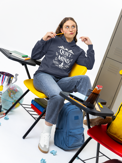 Person wearing a hoodie with 'Quiet Mind' text, sitting in a colorful room with backpack and stationery.