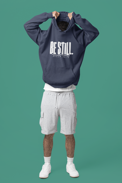 Person wearing a true navy hoodie with 'Be Still. Psalm 46:10' text, pulling up the hood.