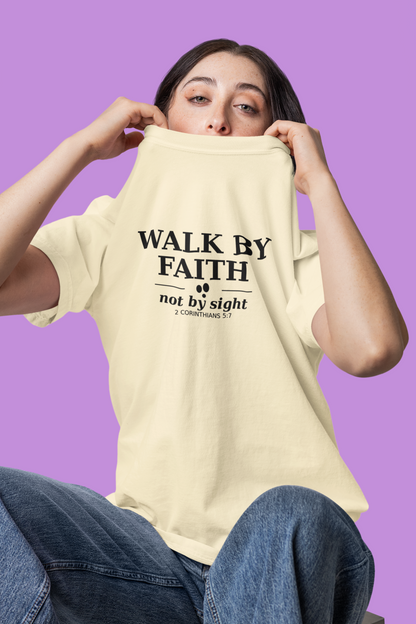 Person wearing an ivory t-shirt with 'Walk by Faith not by sight' text on a purple background