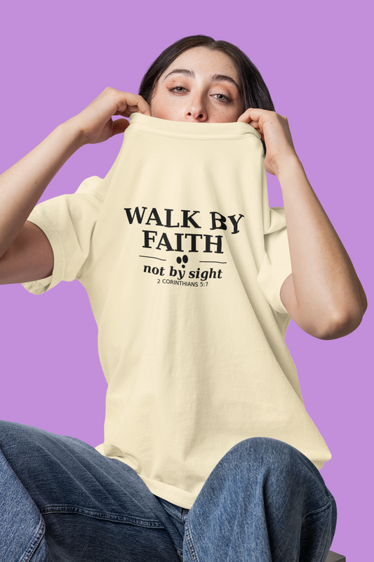 Person wearing an ivory t-shirt with 'Walk by Faith not by sight' text on a purple background