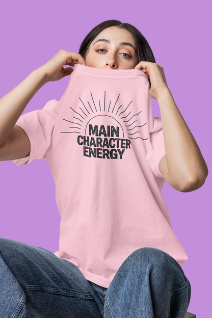 Woman wearing a pink 'Main Character Energy' garment-dyed tee with sunburst graphic."
