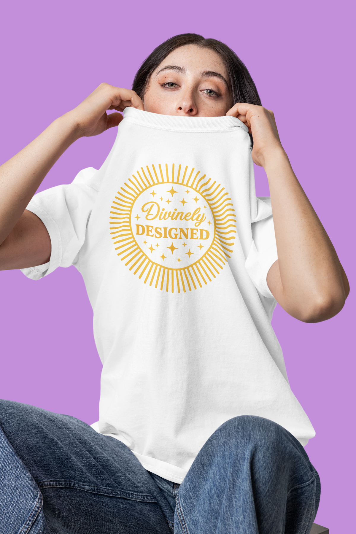 Person wearing a white t-shirt with 'Divinely Designed' text on a purple background