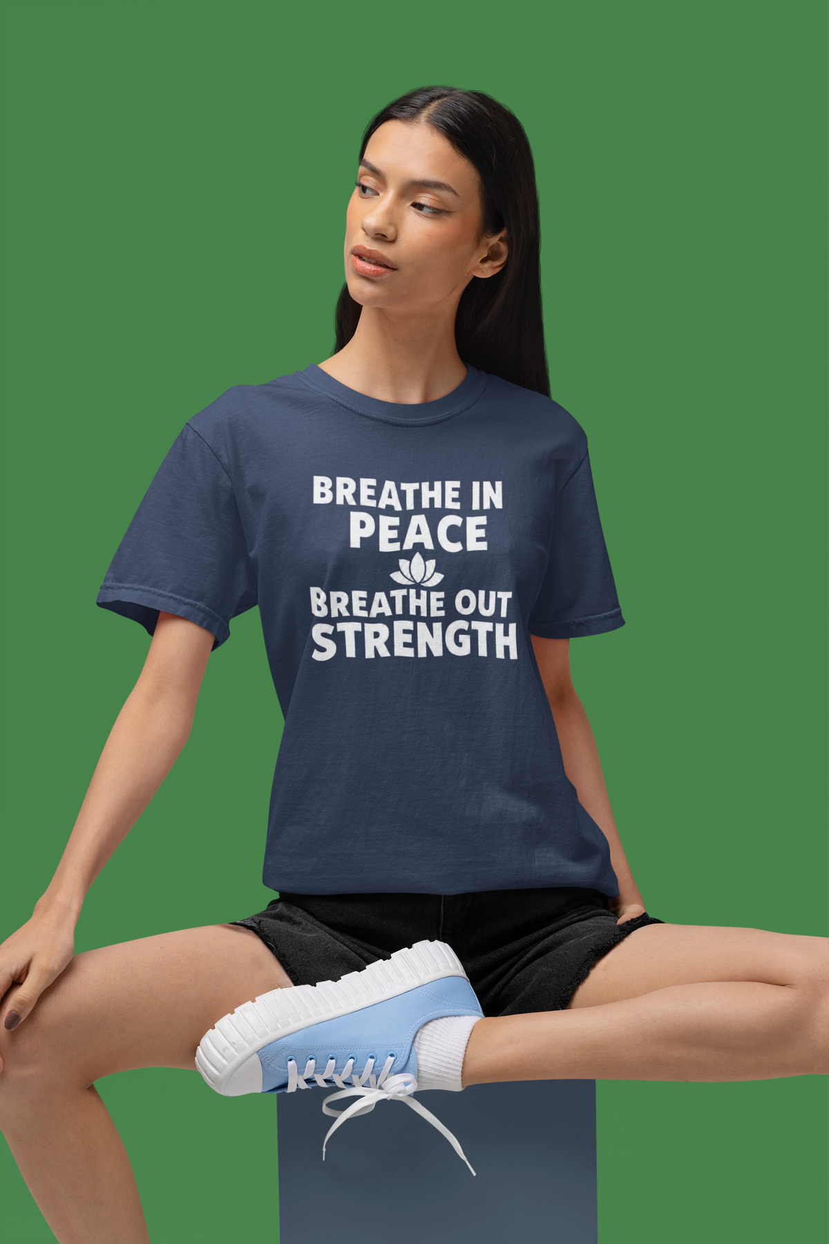 Person wearing a navy blue t-shirt with motivational text on a green background