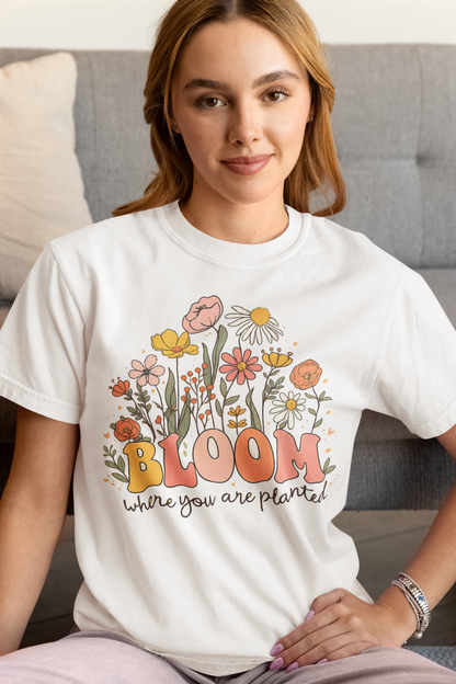 Woman wearing a white t-shirt with floral design and text sitting on a couch.
