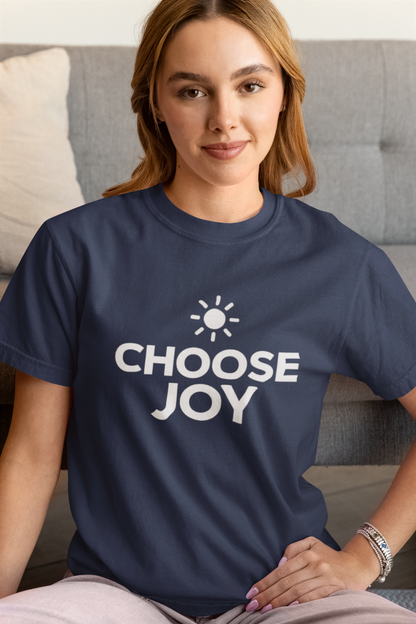Woman wearing a navy blue t-shirt with 'CHOOSE JOY' text, sitting on a couch.