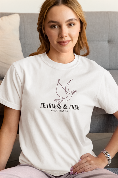 Woman wearing a white t-shirt with a dove illustration sitting on a couch.