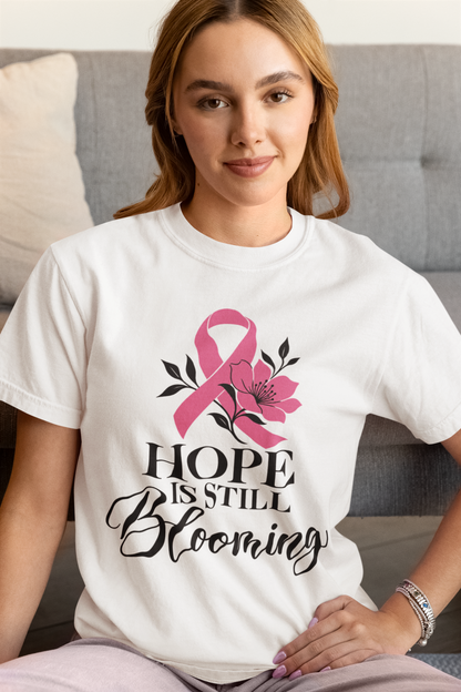 Smiling model wearing a light-colored tee with the “Hope Is Still Blooming” floral design.