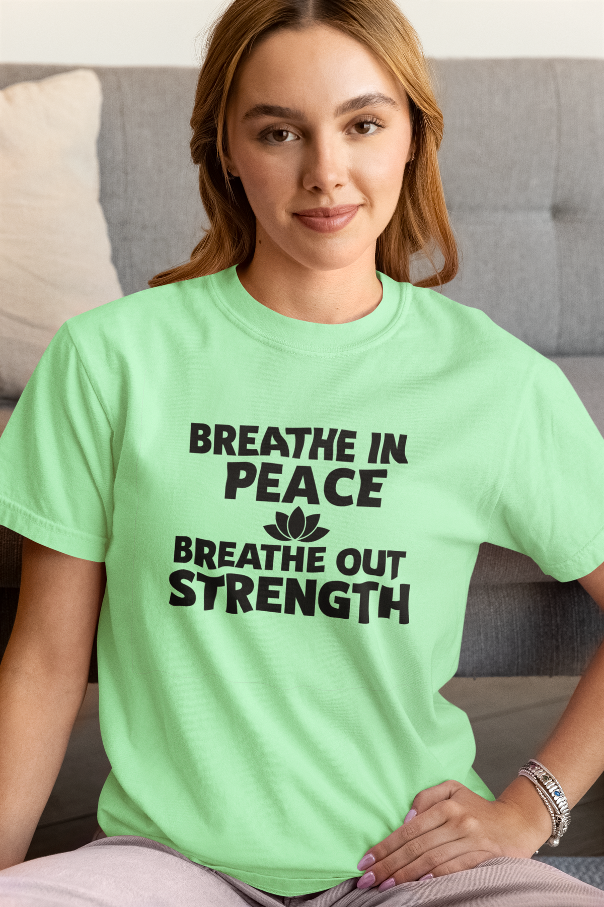 Woman wearing a light green t-shirt with 'Breathe In Peace, Breathe Out Strength' text.