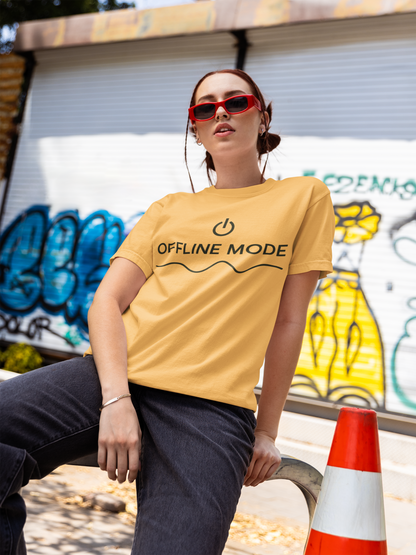 Person wearing a yellow t-shirt with 'OFFLINE MODE' text in front of graffiti.