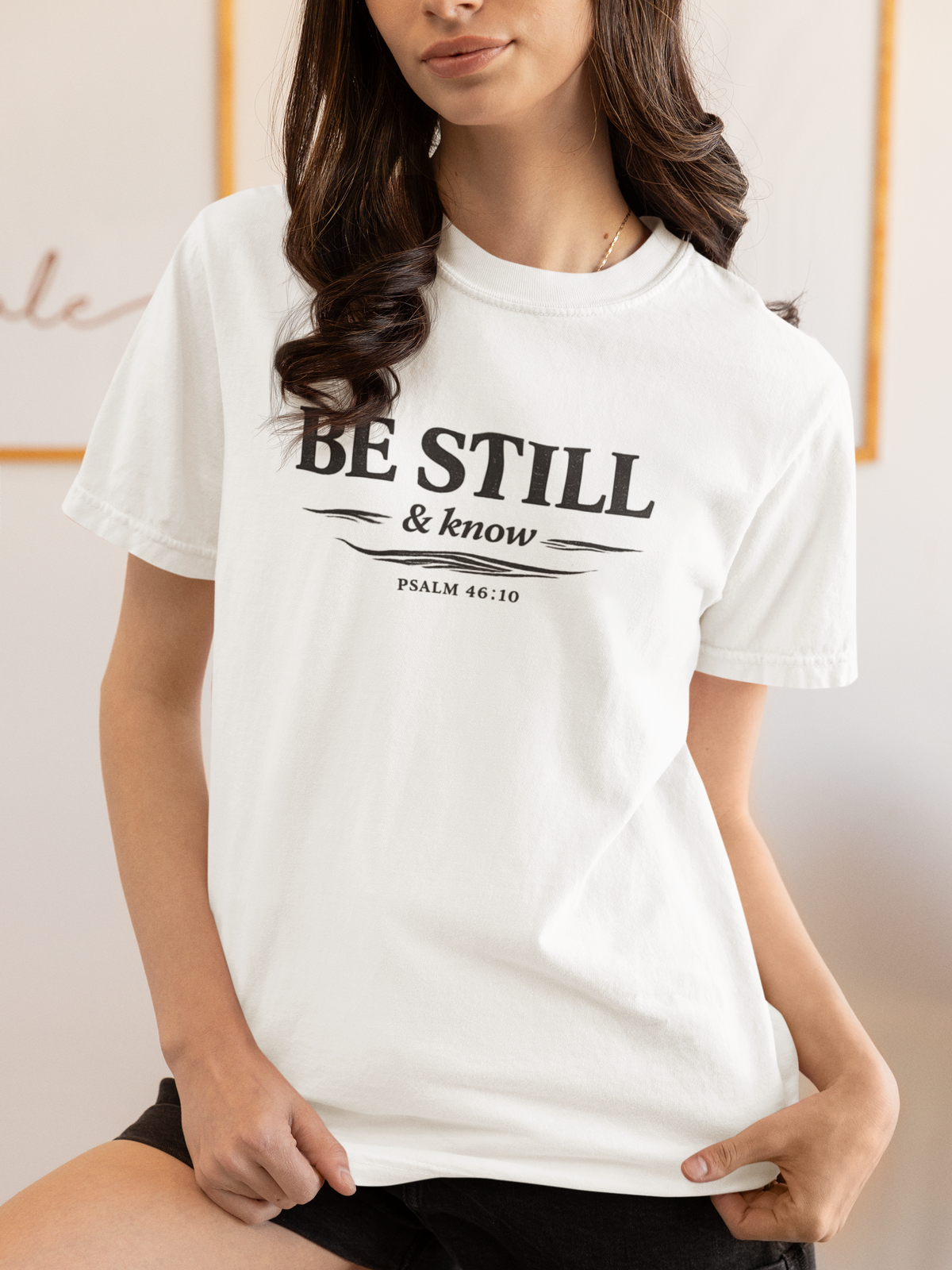Person wearing a white t-shirt with 'Be Still & Know' text