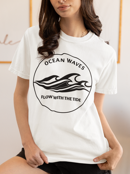 Person wearing a white 'Ocean Waves – Flow with the Tide' garment-dyed tee in a cozy homemade-feel setting.