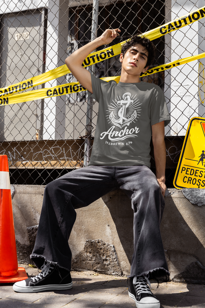 Person wearing a pepper (grayish) t-shirt with an anchor design, sitting on a concrete ledge with caution tape and signs in the background.