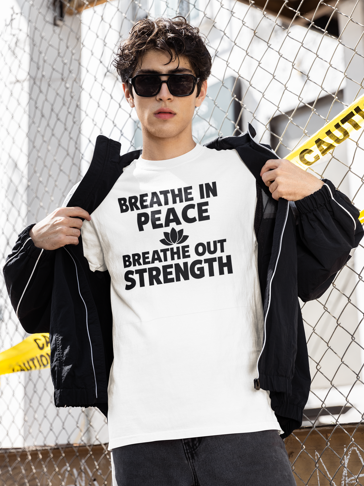 Person wearing a white t-shirt with motivational text, standing against a chain-link fence.