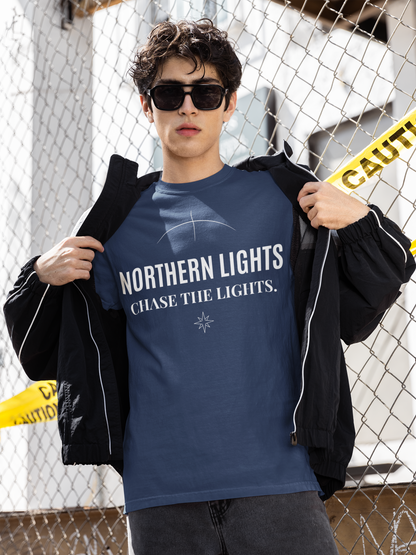 Person wearing a true blue t-shirt with 'Northern Lights Chase the Lights' text, standing in front of a chain-link fence.