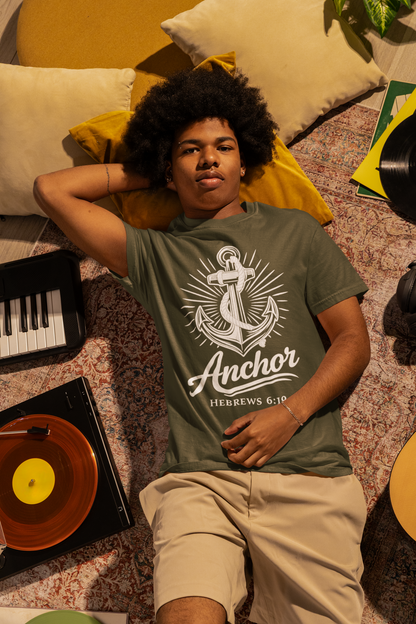 Person wearing a sage green t-shirt with an anchor design, sitting on a patterned couch with music-themed decor.