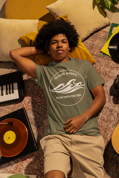 Person wearing a moss 'Ocean Waves – Flow with the Tide' garment-dyed tee, relaxing on a rug with musical instruments.