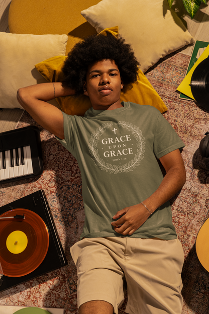 Person wearing a 'Grace Upon Grace' t-shirt lying on a patterned surface with records and a keyboard.