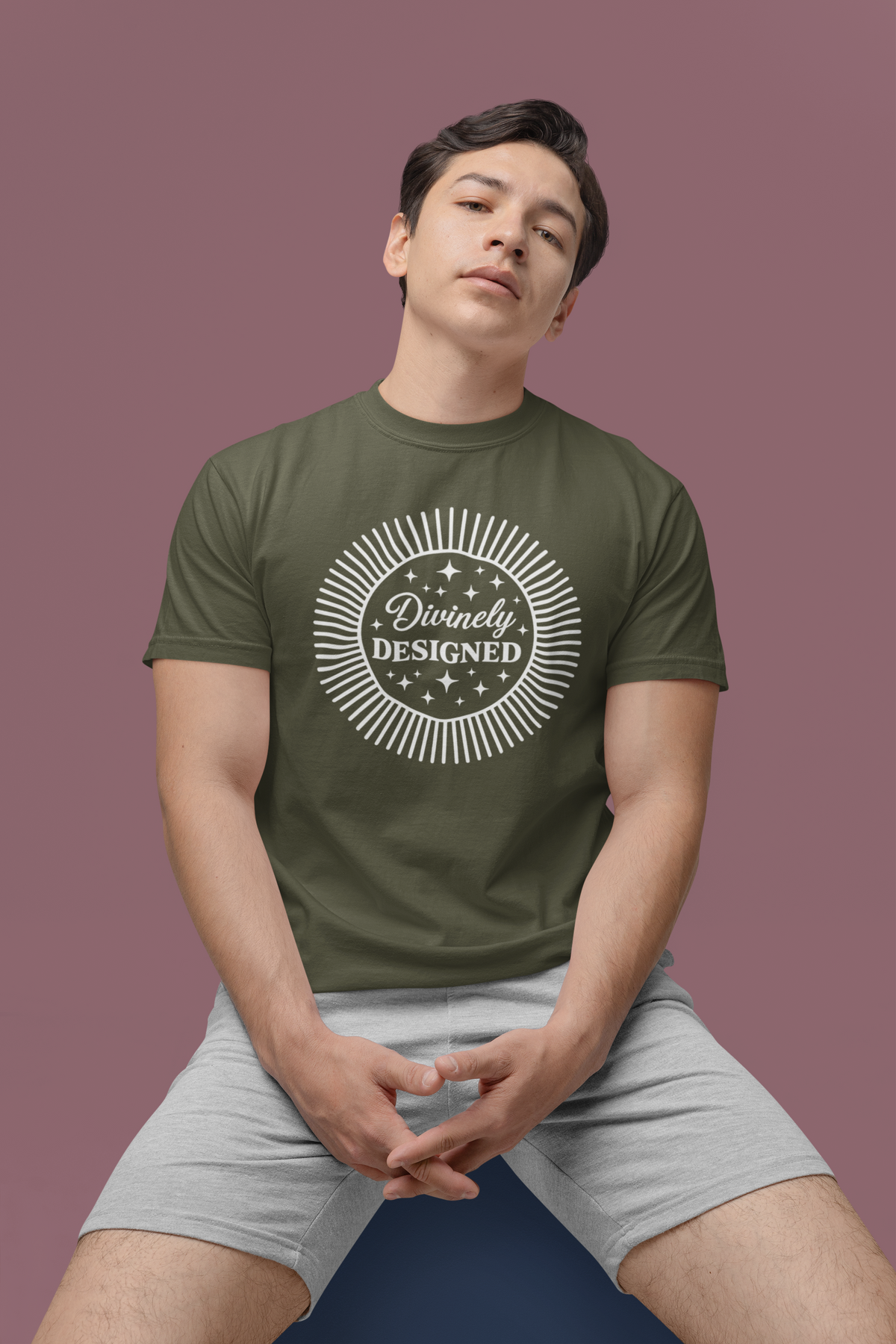Person wearing a sage green t-shirt with 'Divinely Designed' text on a purple background