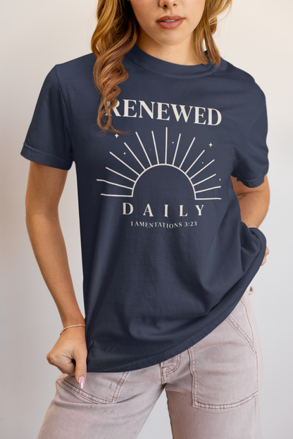 Person wearing a navy blue t-shirt with 'Renewed Daily' text and sun graphic.