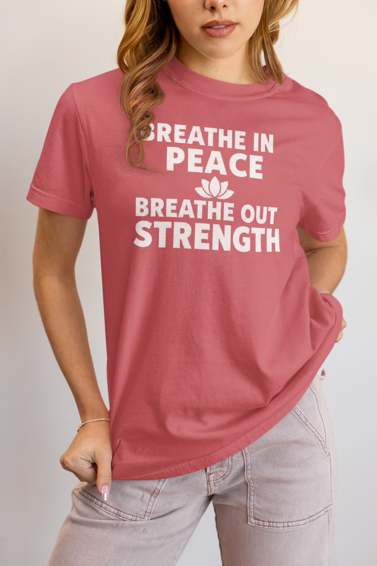 Person wearing a pink t-shirt with motivational text on a plain background
