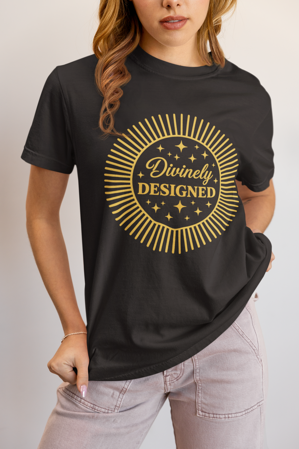 Person wearing a black t-shirt with 'Divinely Designed' gold text and star graphics.