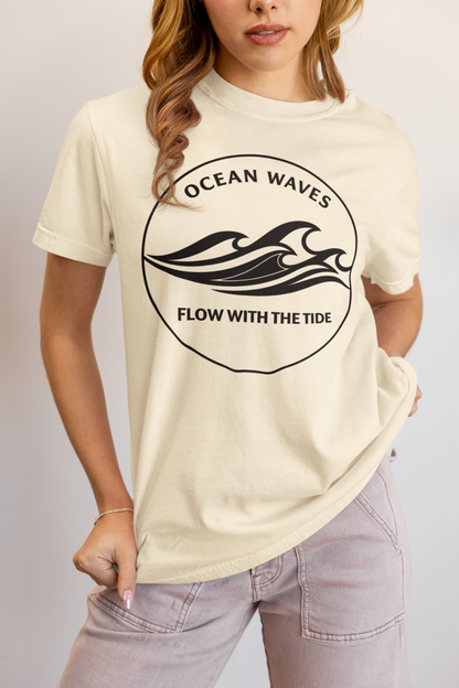 Person wearing an ivory 'Ocean Waves – Flow with the Tide' garment-dyed tee in a studio setting.