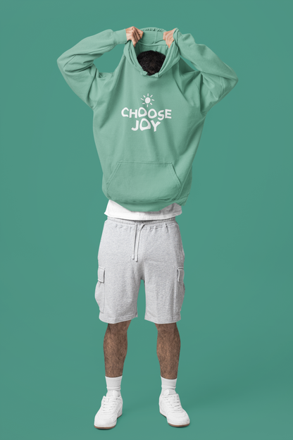 Person wearing a seafoam green hoodie with 'CHOOSE JOY' text on a solid background
