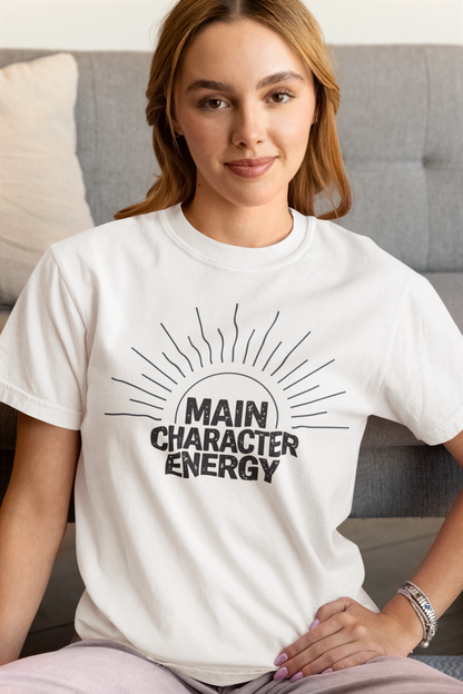Woman wearing a white 'Main Character Energy' garment-dyed tee with sunburst graphic."
