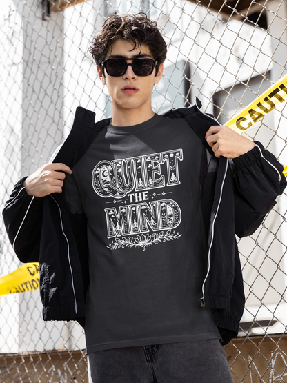 Person wearing a black hoodie with 'Quiet the Mind' text, standing against a chain-link fence.