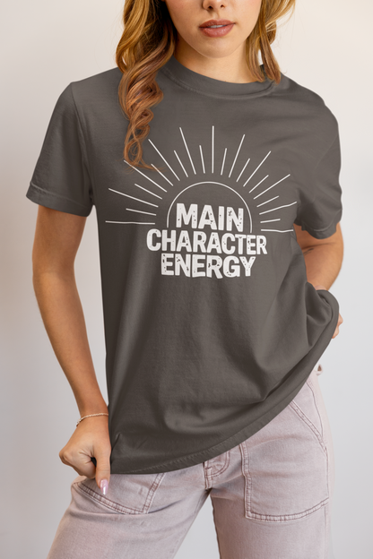 Woman wearing a pepper 'Main Character Energy' garment-dyed tee with sunburst graphic."