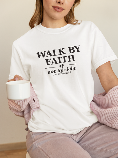 Person wearing a white t-shirt with 'Walk by Faith not by sight' text, holding a cup.