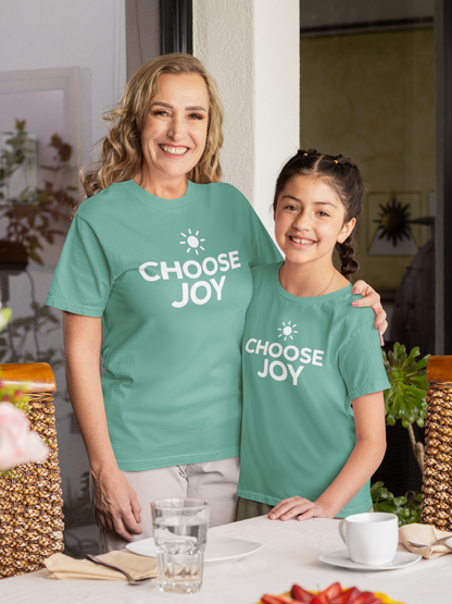Woman and young girl wearing seafoam (green) t-shirts with motivational text, standing outdoors.