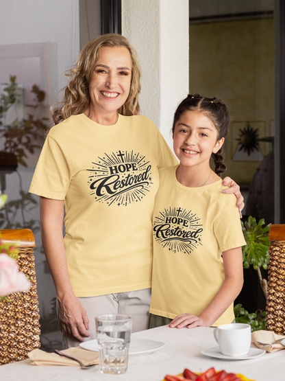 Woman and young girl wearing matching yellow t-shirts with 'Hope Restored' text.