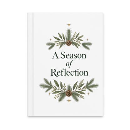 A Season of Reflection white hardcover journal with evergreen branches, pinecones, gold stars, and dark-green lettering.